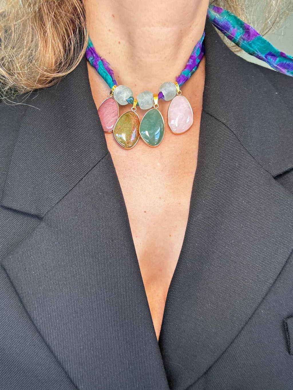 The necklace worn over a black blazer, the four stones sitting close at the base of the neck