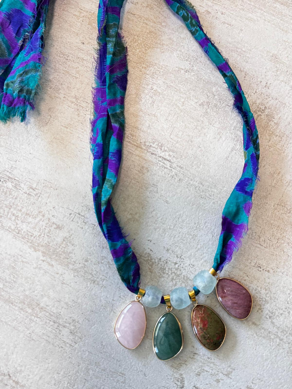 The necklace laid flat, showing the raw-edged sari silk ribbon running to both ends