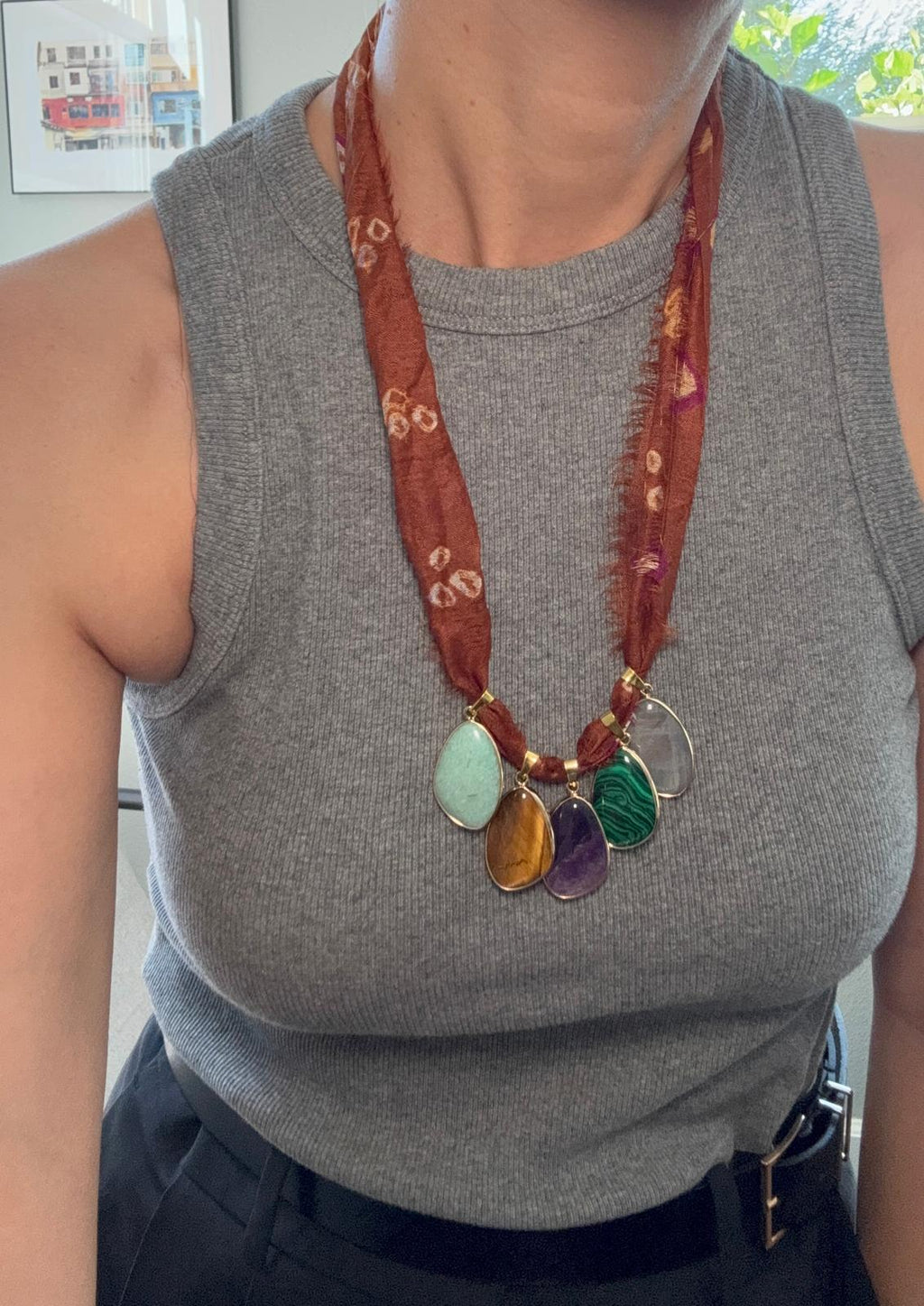 The necklace worn long over a grey top, the sari silk hanging to mid-chest