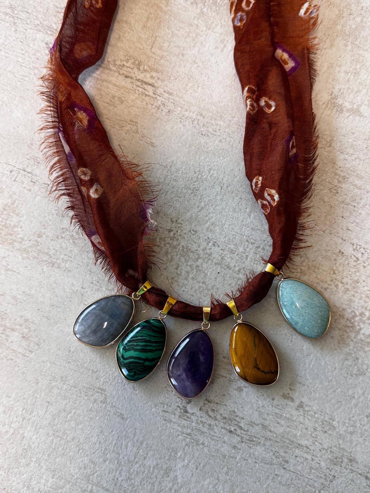 The five stones laid flat: labradorite, malachite, amethyst, tiger's eye and amazonite in gold-plated bezels