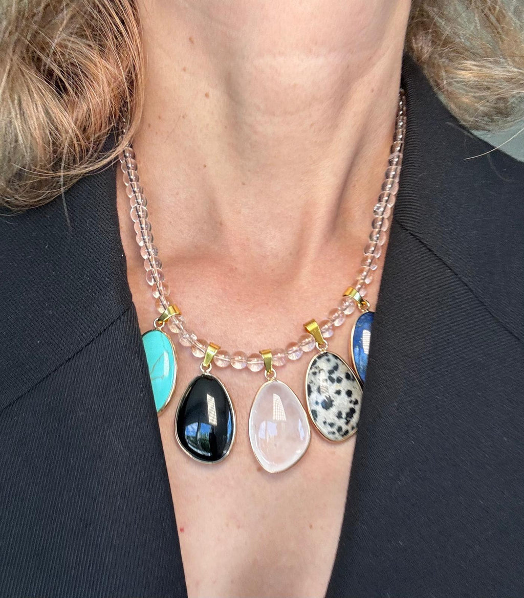 The necklace worn over a grey top, the stones sitting in a row below the collarbone