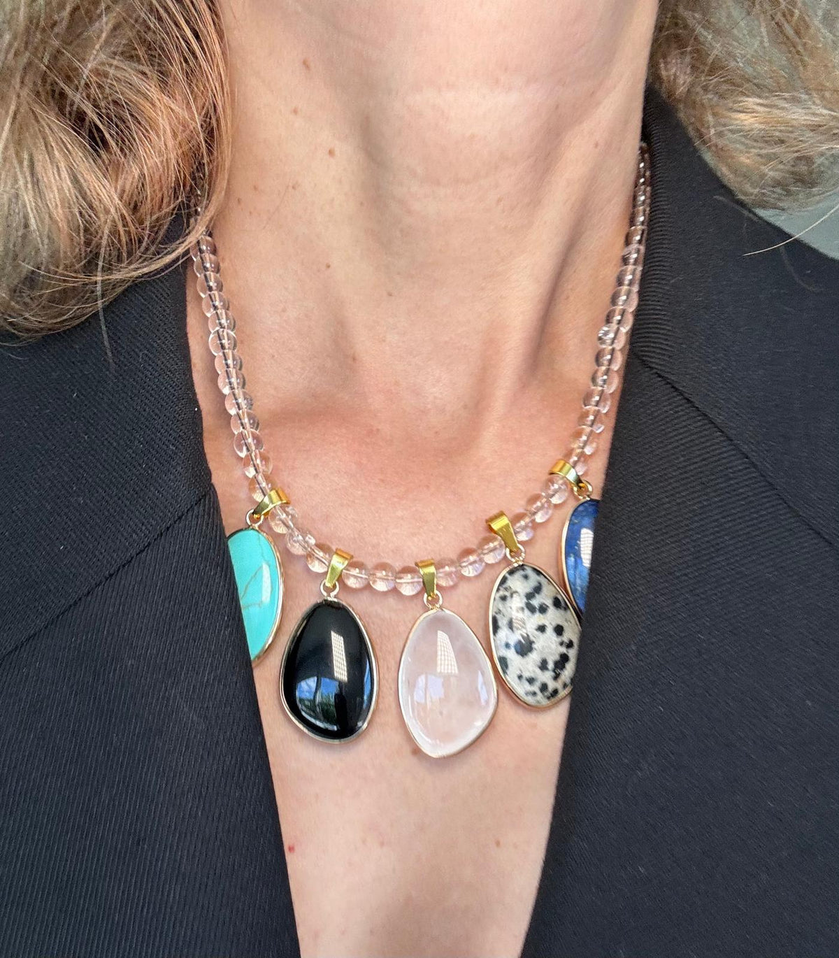The necklace worn over a grey top, the stones sitting in a row below the collarbone