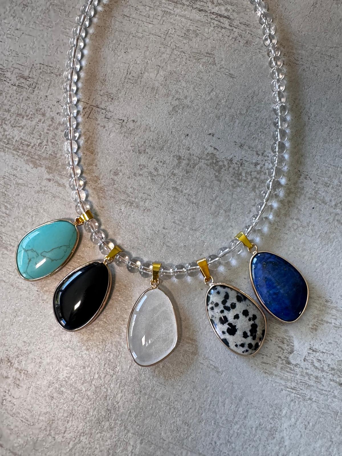 The five stones: turquoise, black obsidian, milky quartz, dalmatian jasper and lapis lazuli, each in a gold-plated bezel