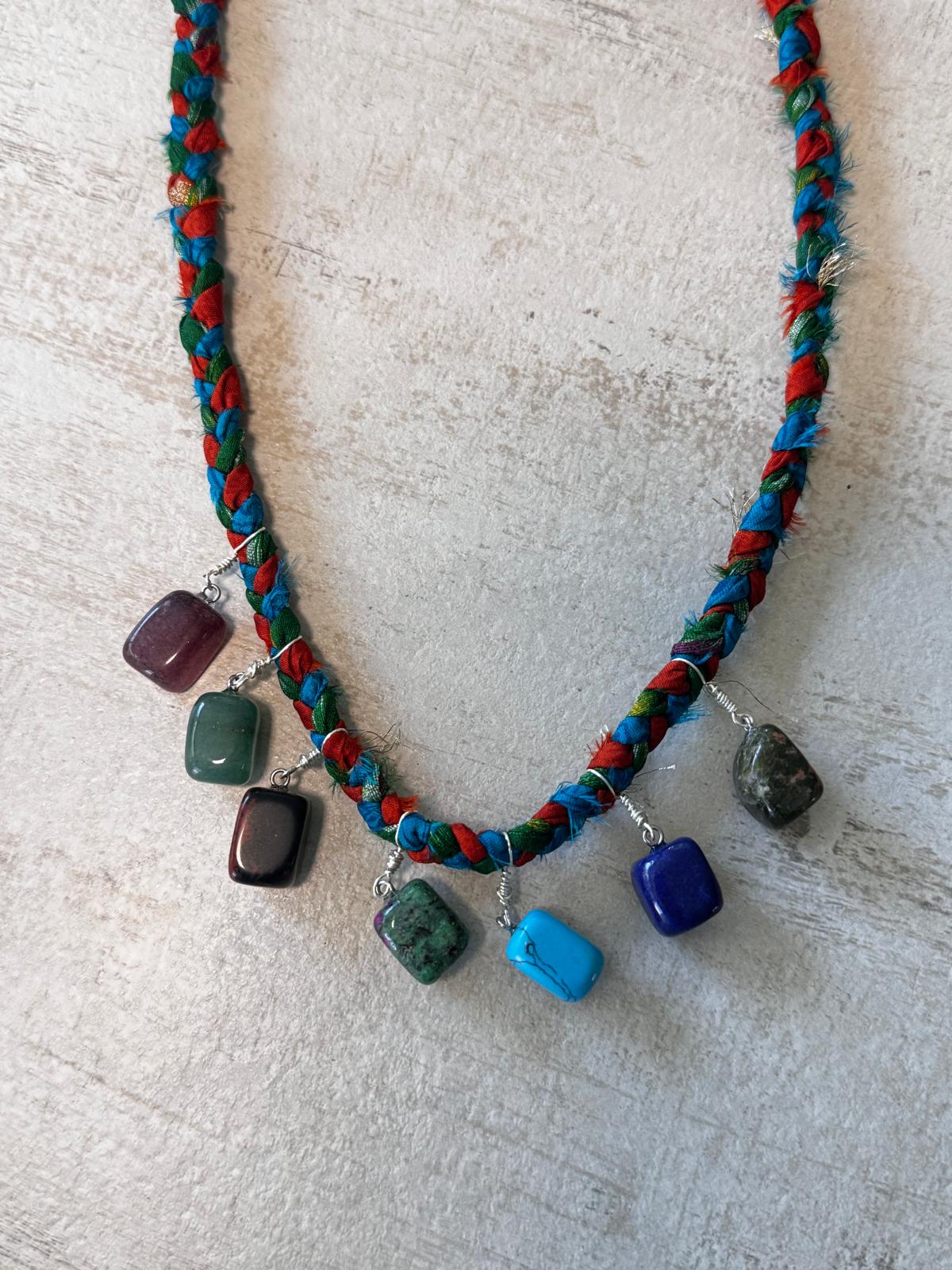 A braided vintage sari silk necklace in red, teal and green with seven wire-wrapped tumbled stones hanging along the front