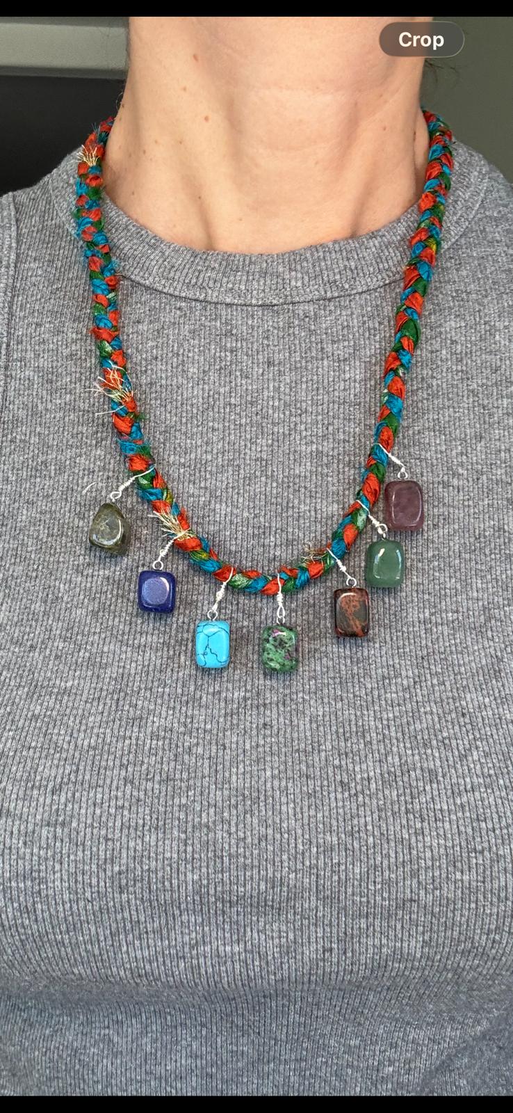 The braided sari silk necklace worn over a grey top, the seven stones sitting just below the collarbone