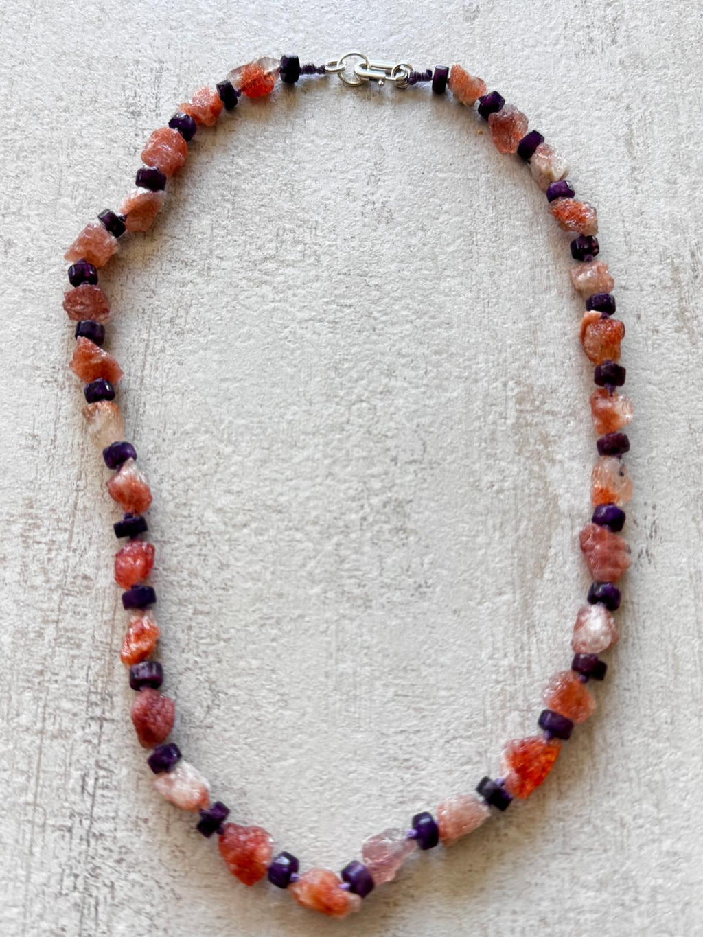 The necklace laid flat — a ring of rough sunstone nuggets alternating with flat lepidolite discs, sterling rectangle clasp at the top