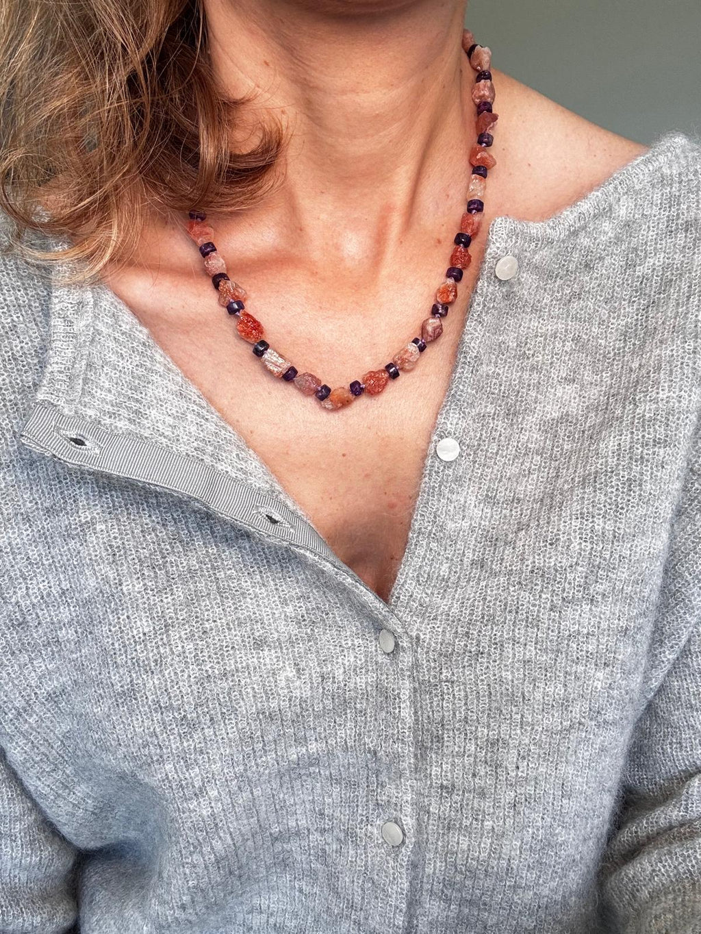 Close view of the necklace worn, showing the glitter inside the unpolished sunstone