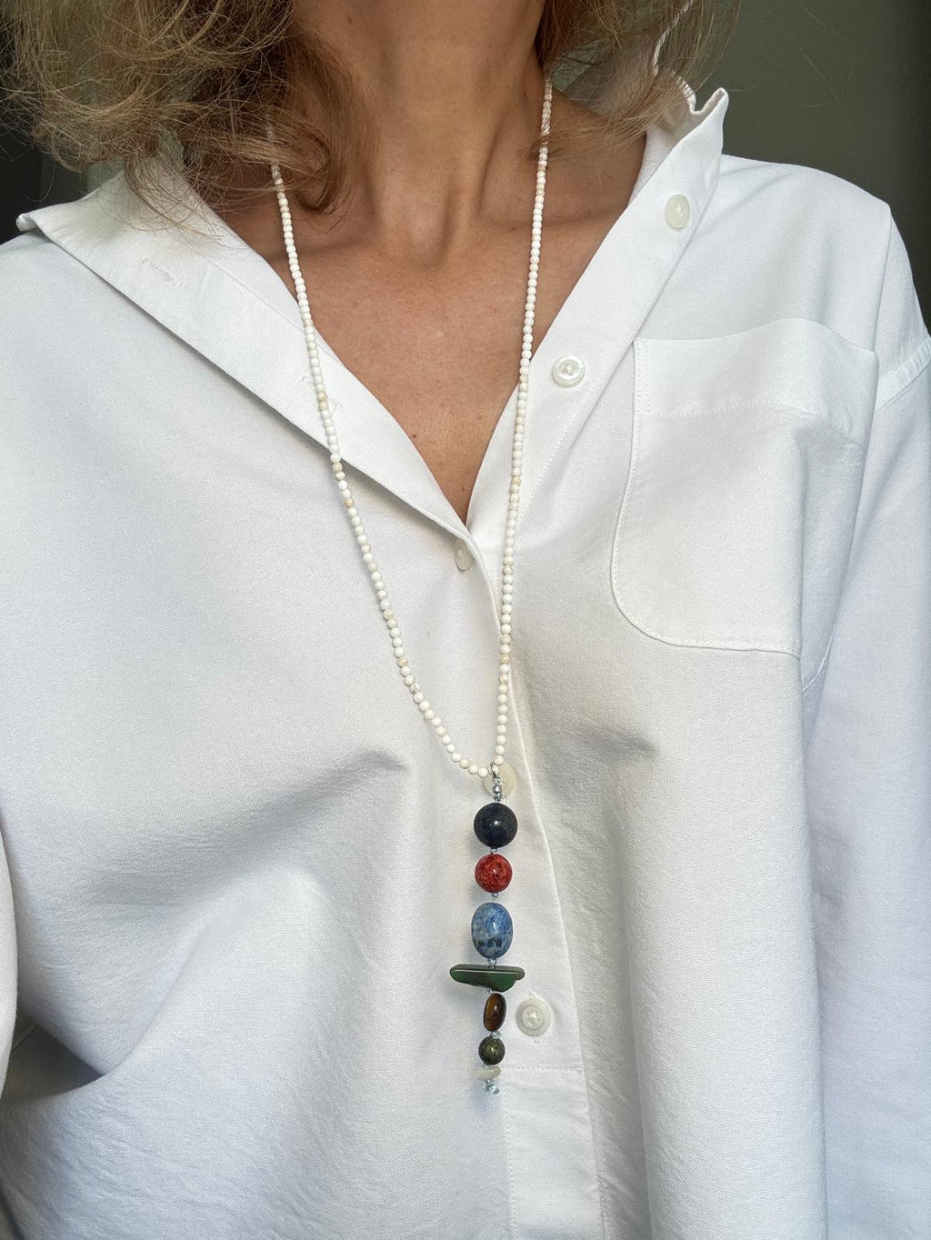 The white howlite necklace worn long over a white shirt, the stacked stone drop hanging at the sternum