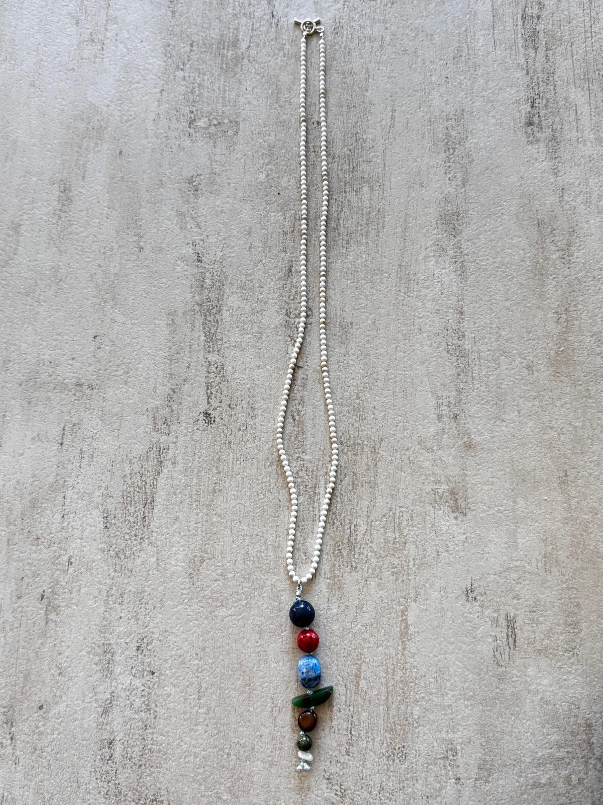 The full necklace laid flat — a fine white howlite strand with a single vertical drop of stacked stones and a sterling toggle clasp