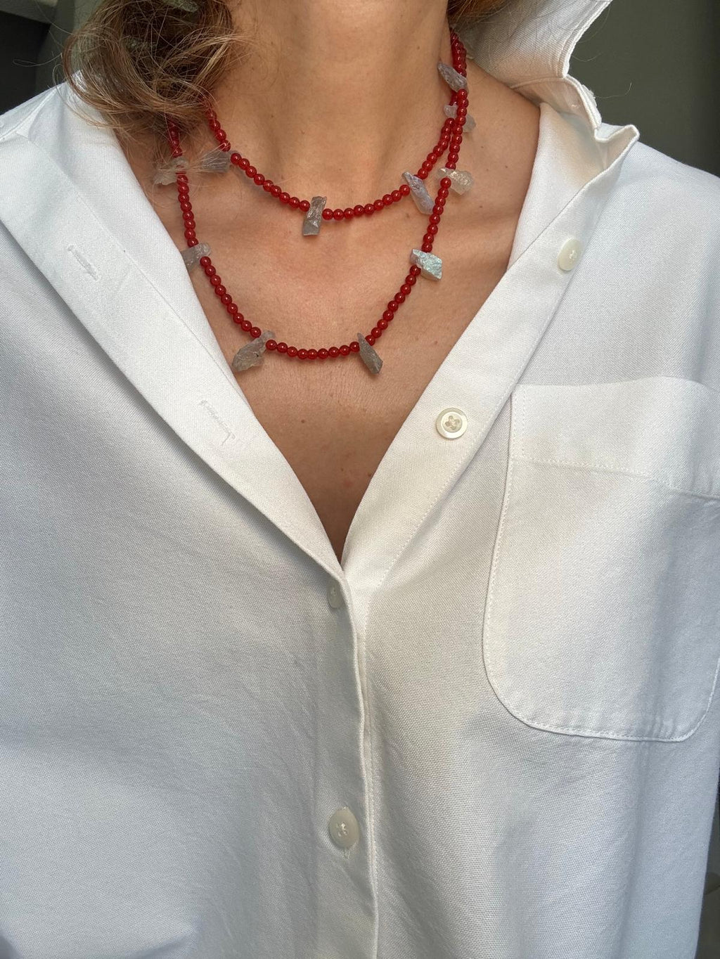 The carnelian necklace worn doubled at the throat, rough pale labradorite chunks spaced along two deep red strands