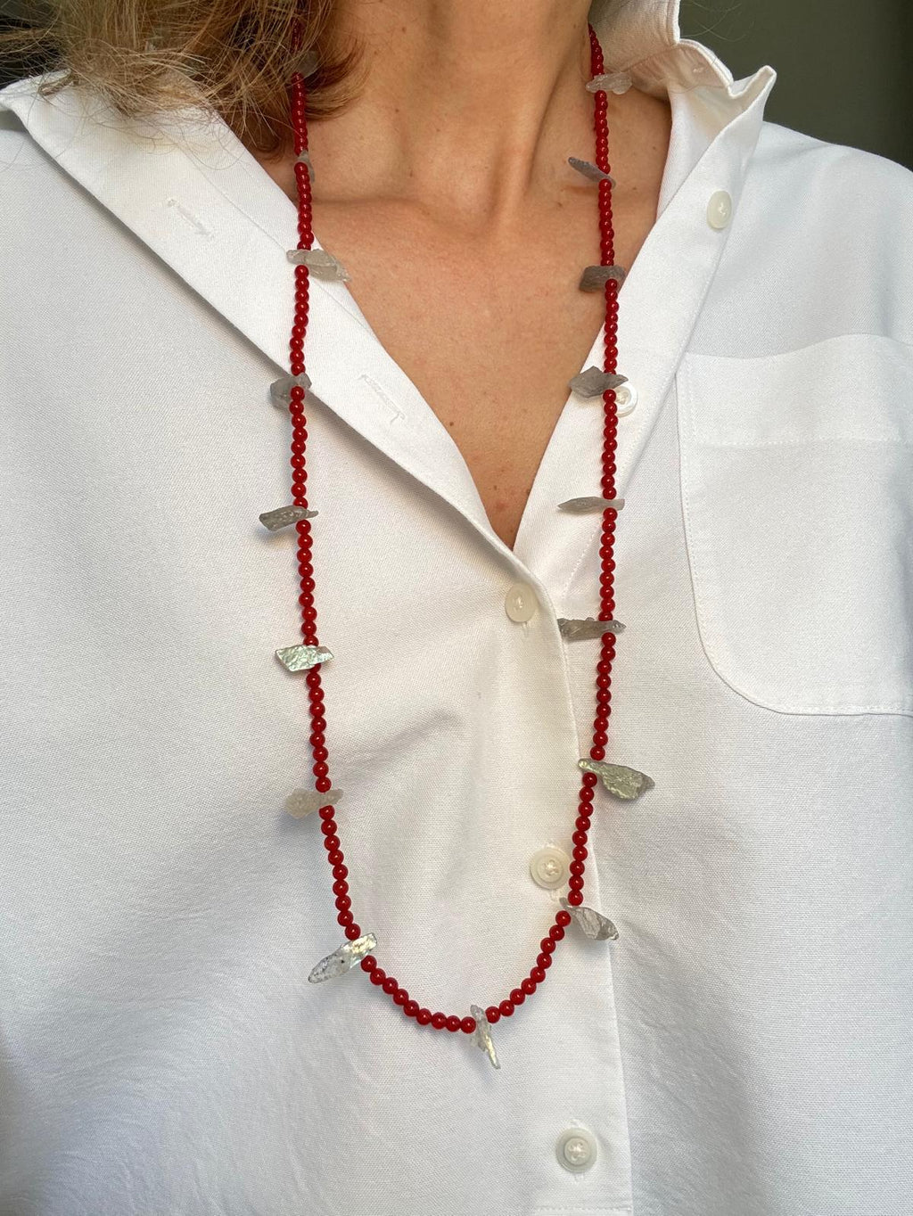 The same necklace worn long as a single strand over a white shirt
