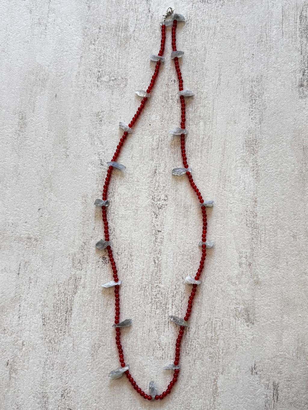 The full length of the necklace laid flat, rough labradorite chunks evenly spaced along the carnelian strand