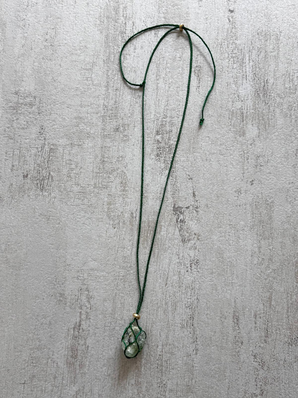 Full view of the raw prehnite pendant necklace on its green cord