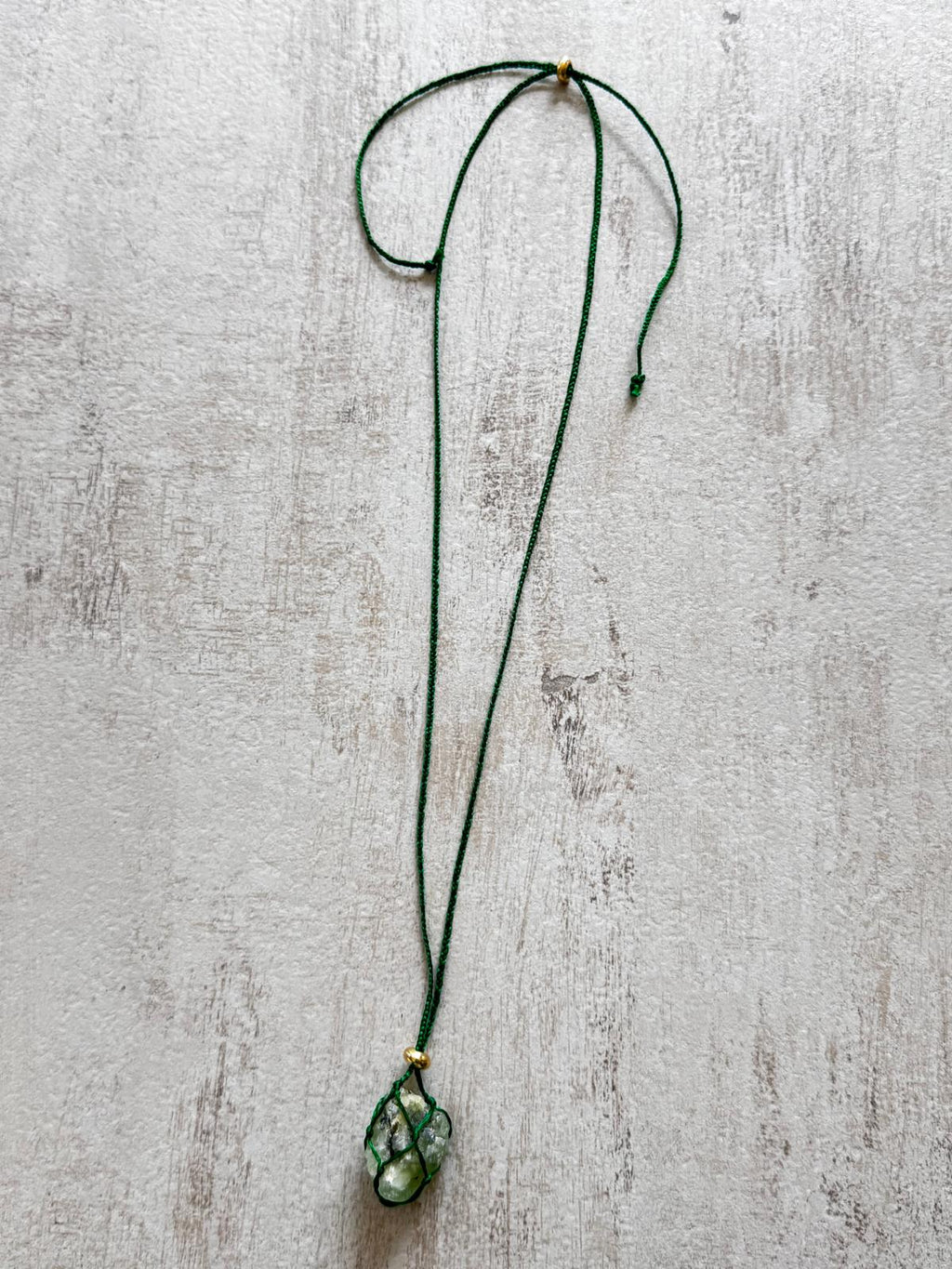 The green braided cord laid out showing the sliding adjuster and gold-plated bead