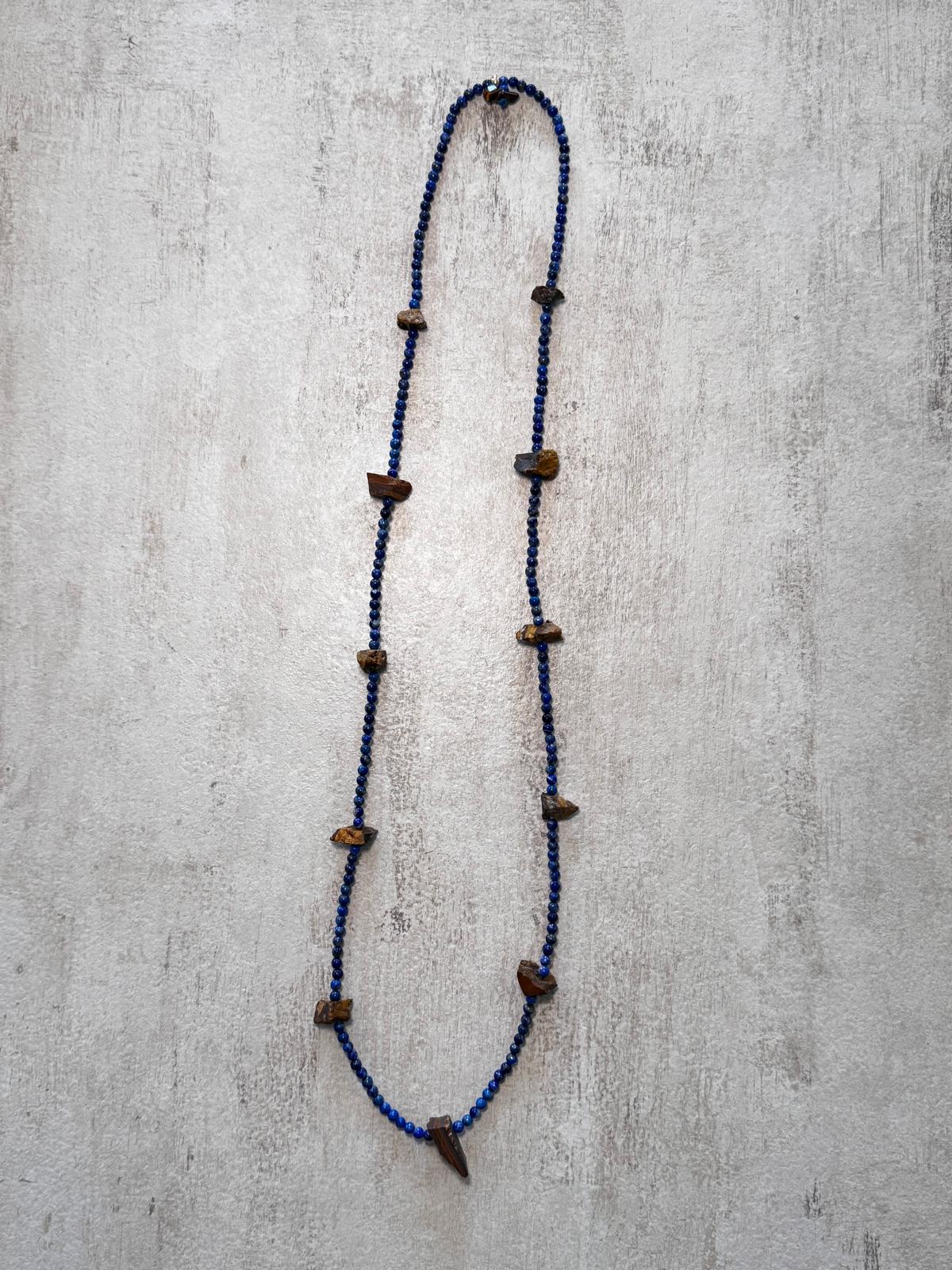 The full length of the necklace laid flat — a long rope of small lapis lazuli beads with rough tiger's eye nuggets spaced along it