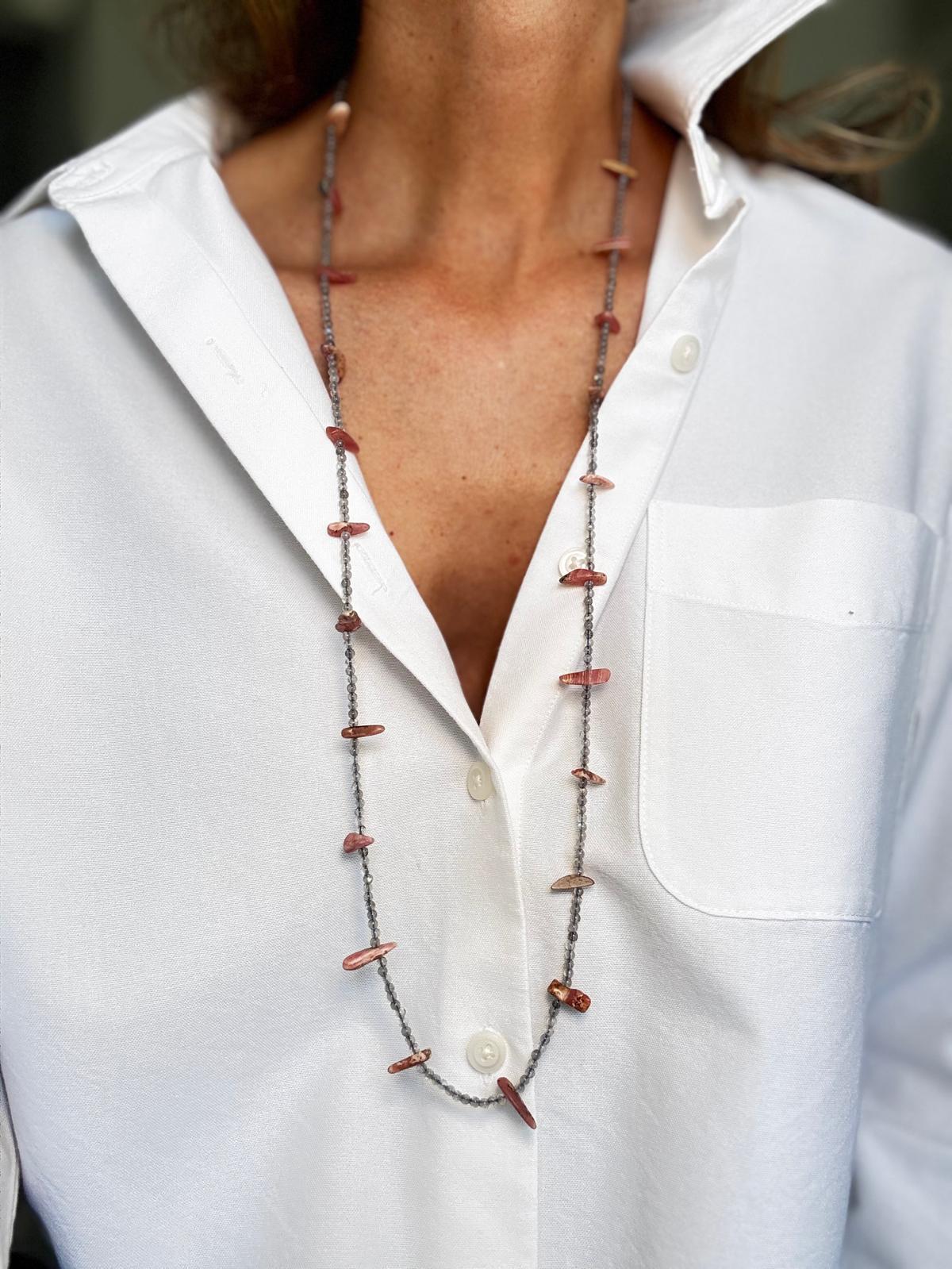 The same necklace worn long as a single strand over a white shirt