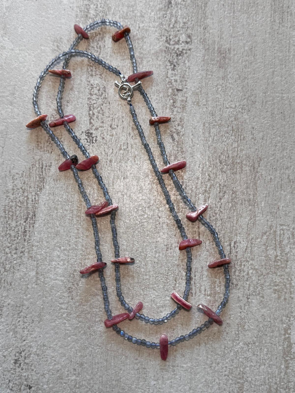 The necklace laid flat and doubled, showing the sterling toggle clasp and the rose-pink rhodochrosite slices