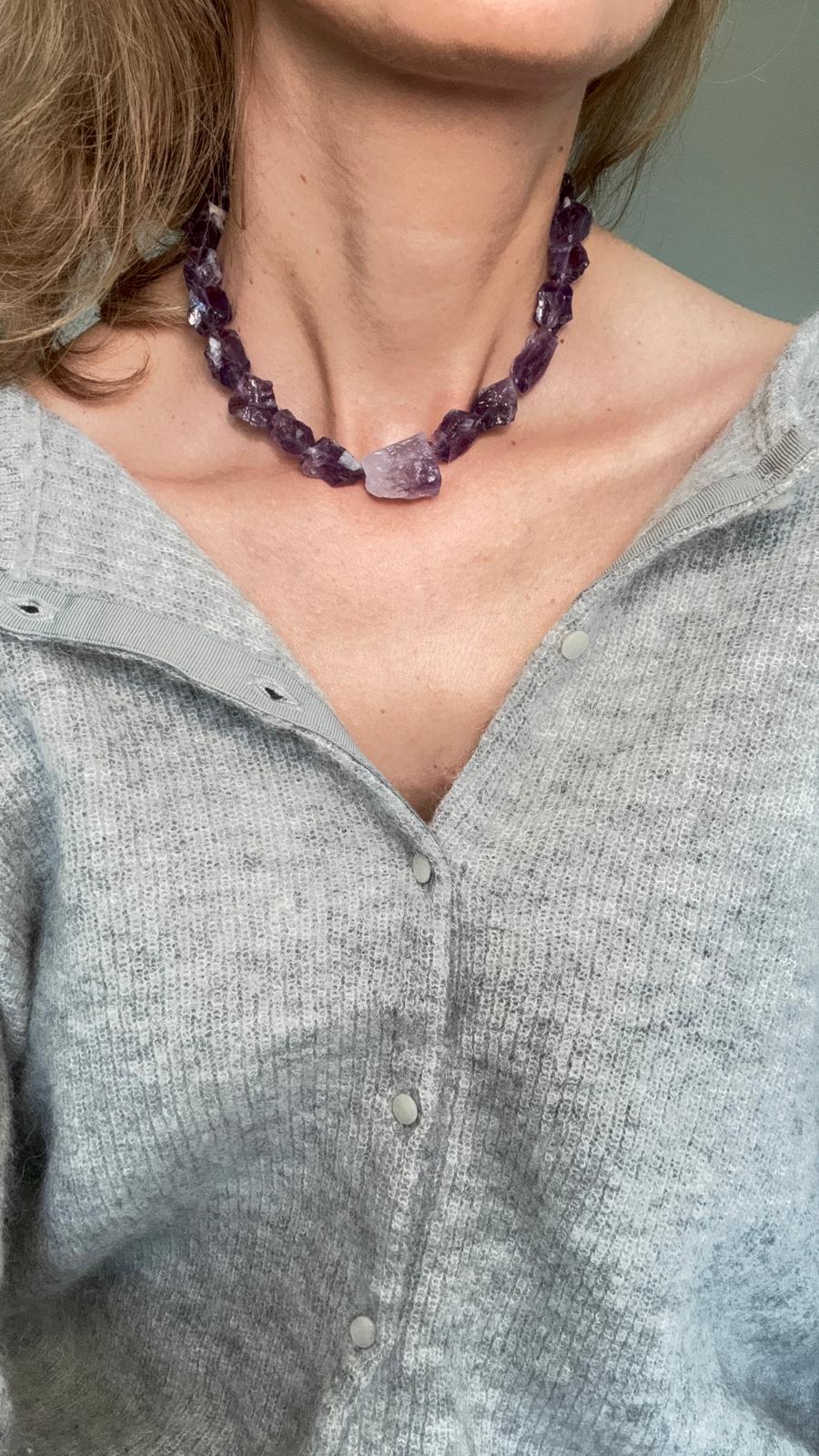 The necklace worn close at the base of the neck, showing the weight and the rough crystal faces