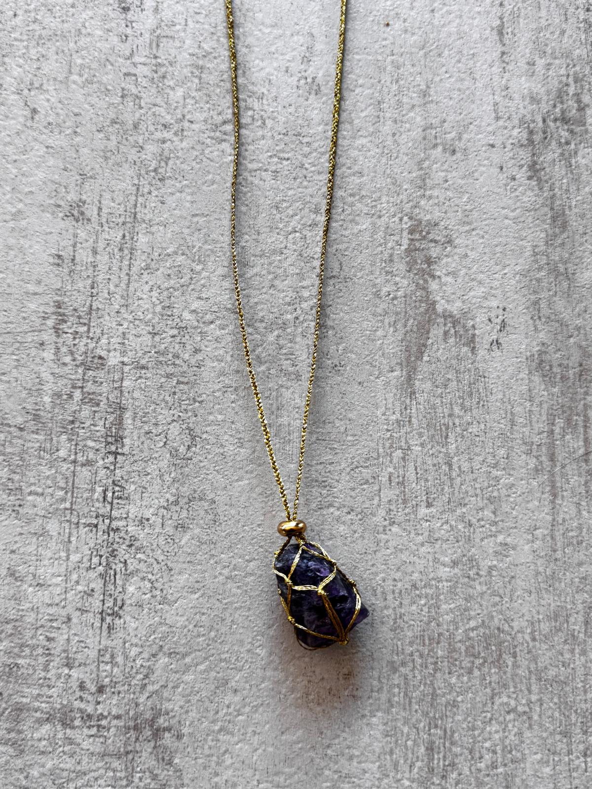 Close view of the dark amethyst caught in the gold braid, with a gold-plated spacer above it