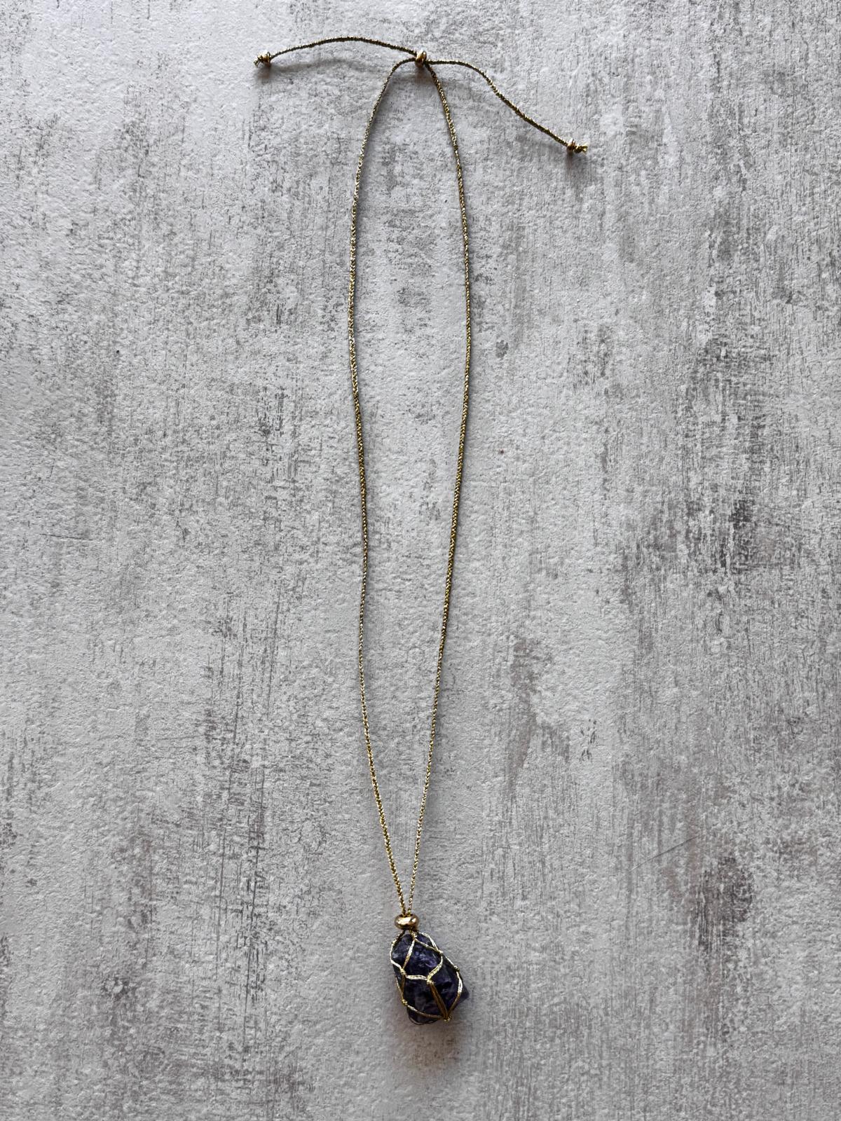 The full necklace laid flat, showing the braided gold cord and the sliding knots that adjust the length