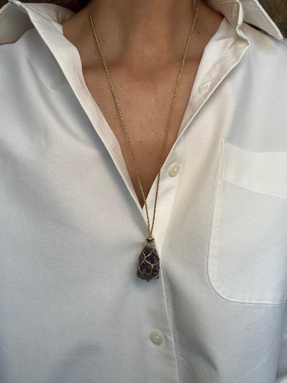 The pendant worn, the raw amethyst dark against a white shirt