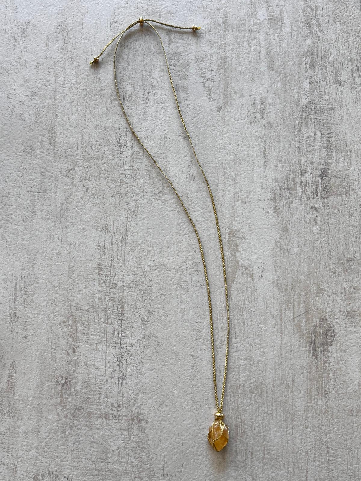 The full necklace laid flat, showing the braided golden cord and the sliding knots that adjust the length