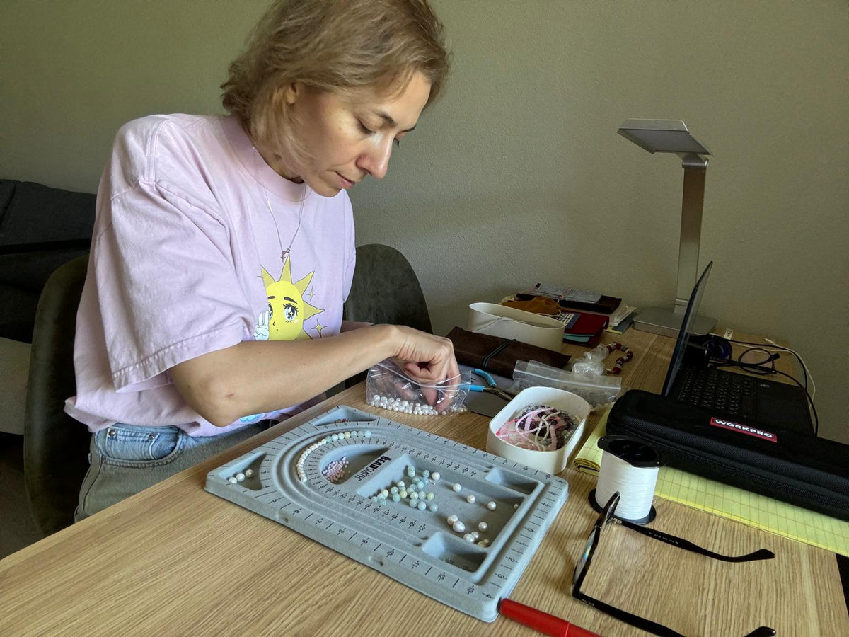 Nuné laying out stones on the bead board at her studio table