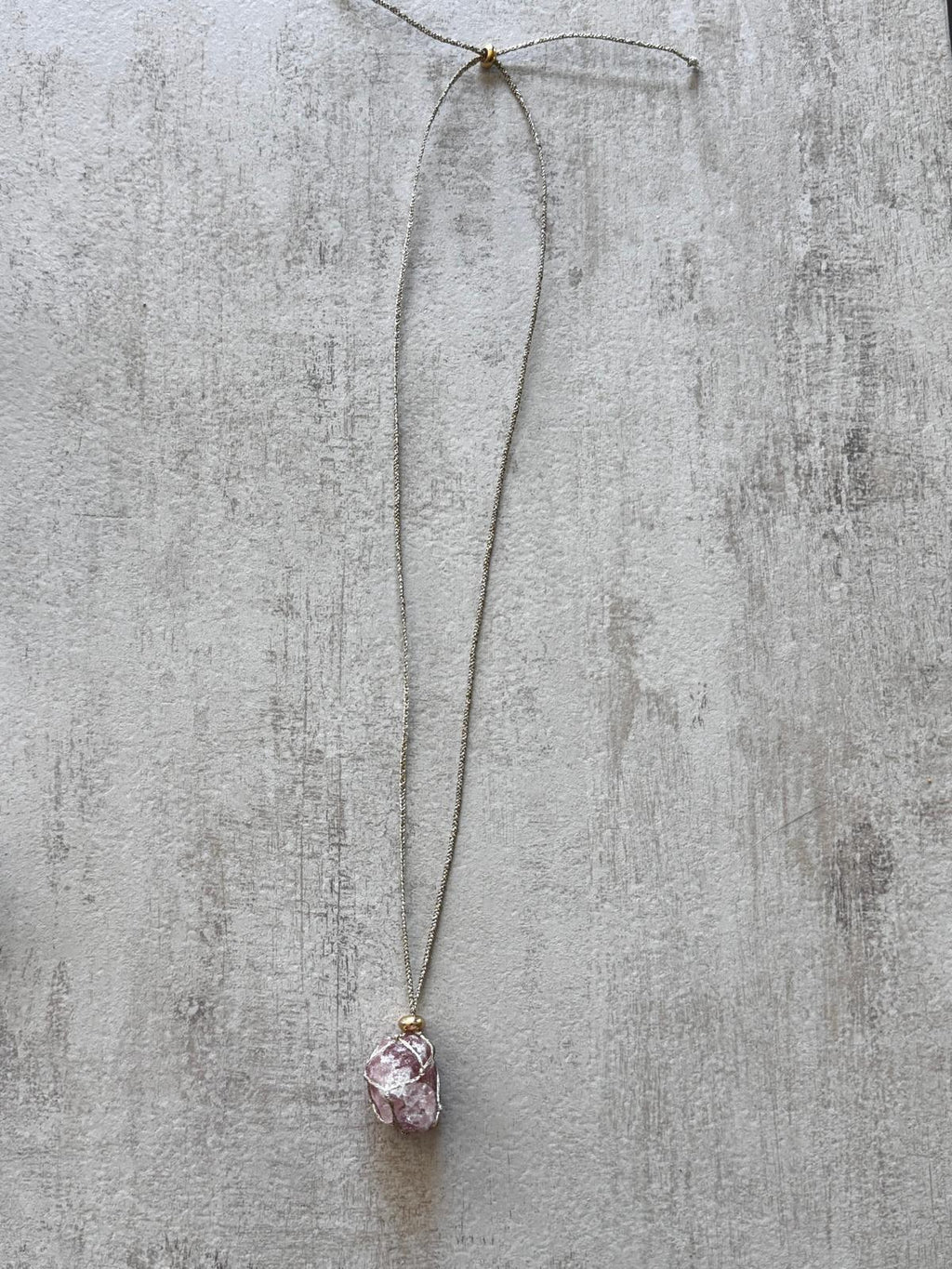 The full necklace laid flat, showing the braided gold cord and the sliding knots that adjust the length