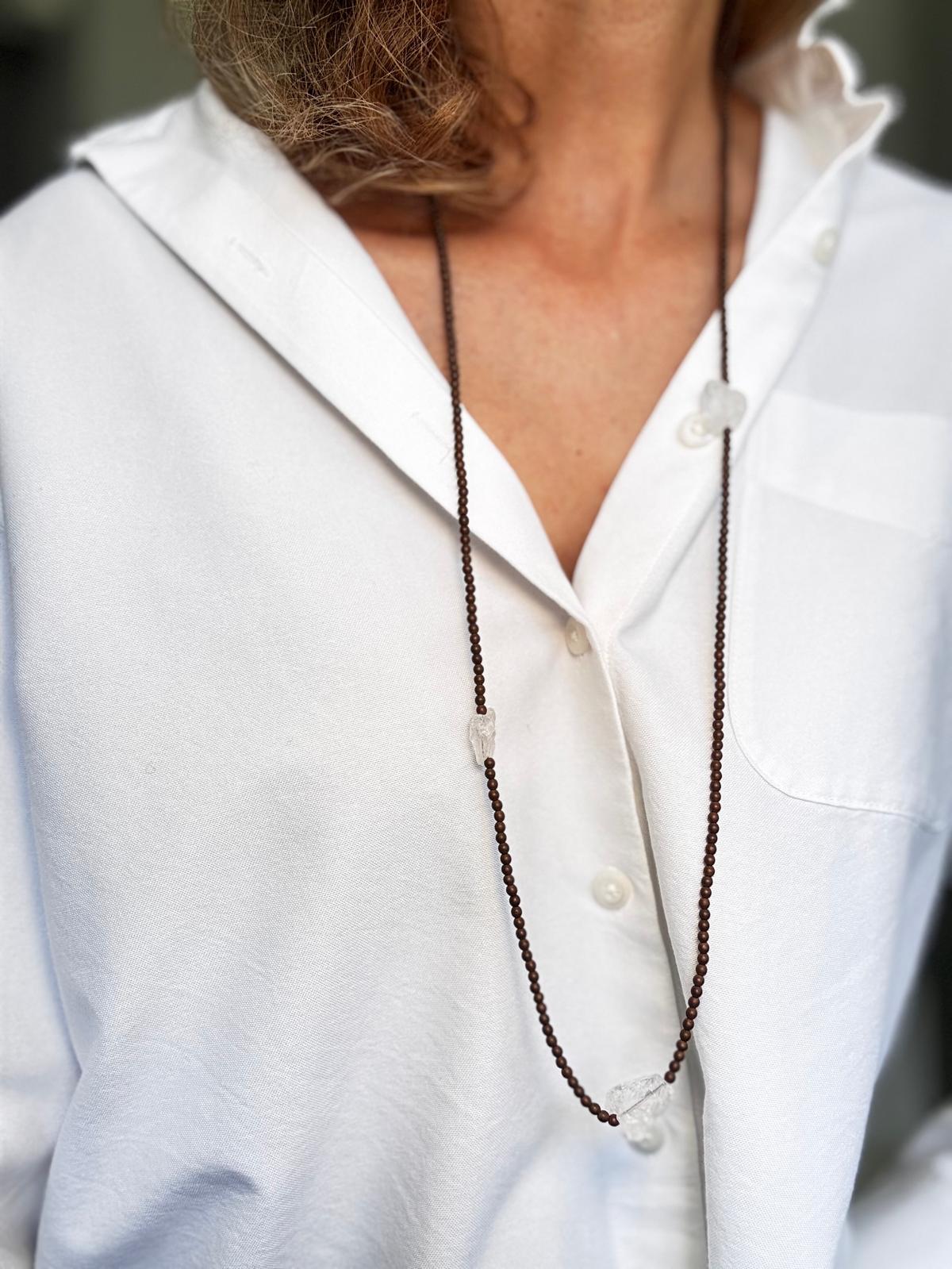 The necklace worn long, the raw quartz sitting against a white shirt