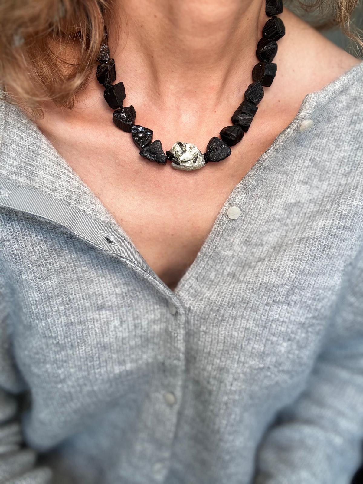 The raw black tourmaline collar worn over a grey cardigan, the pale green prehnite sitting at the centre front