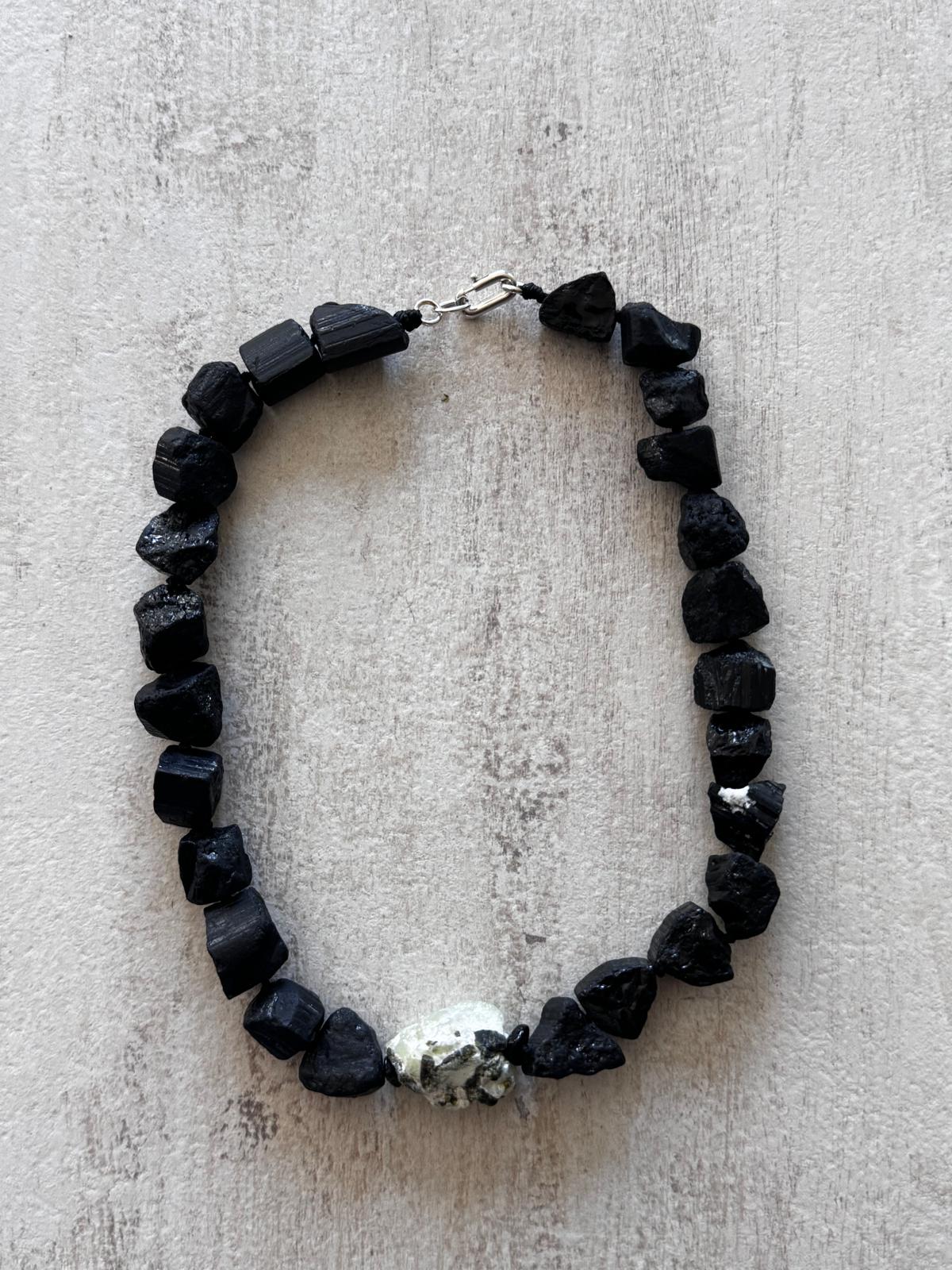 The necklace laid flat — a closed ring of unpolished black tourmaline chunks with one prehnite nugget and a sterling silver clasp