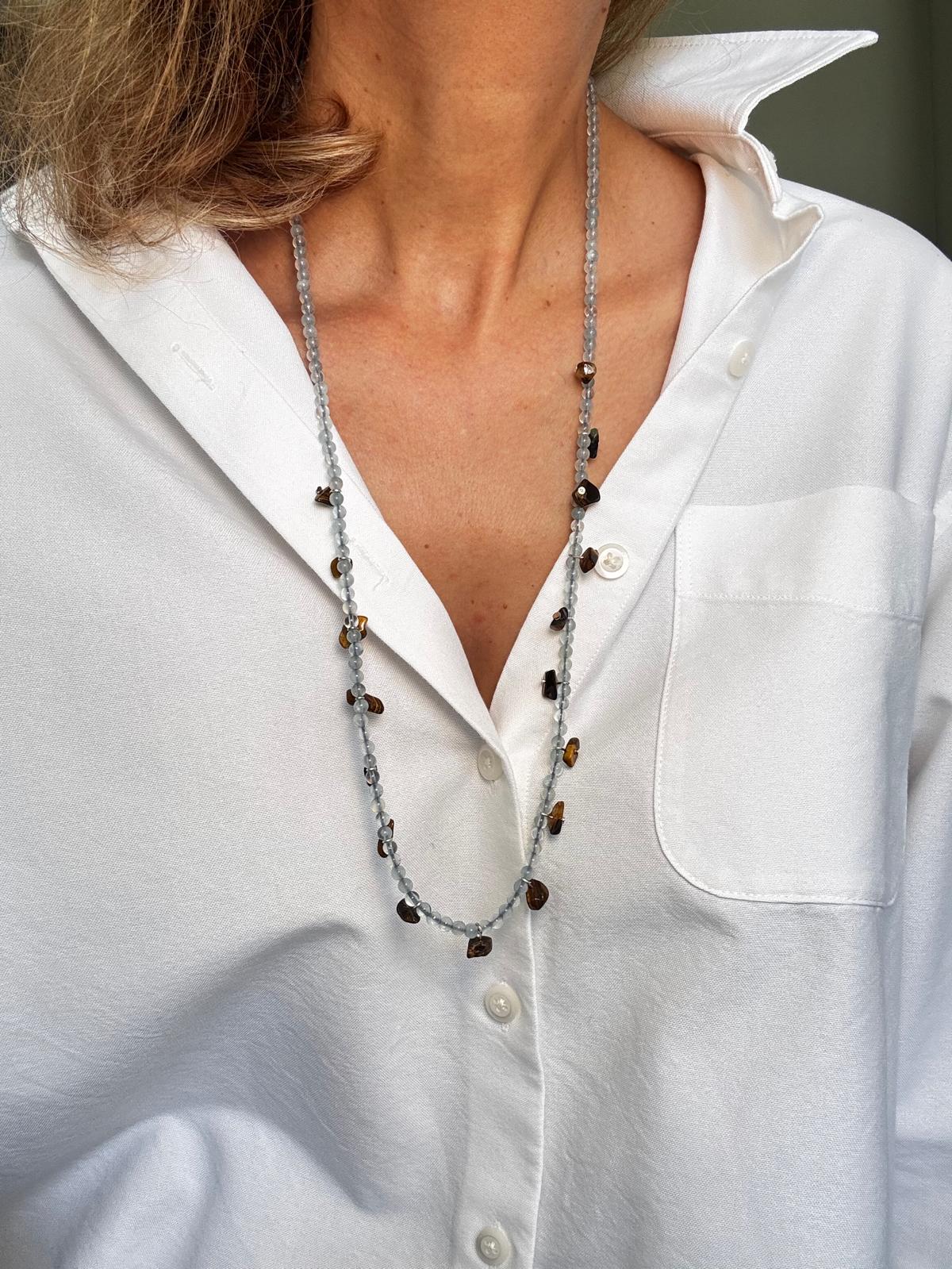 The same necklace worn long as a single strand over a white shirt, tiger's eye nuggets scattered down its length
