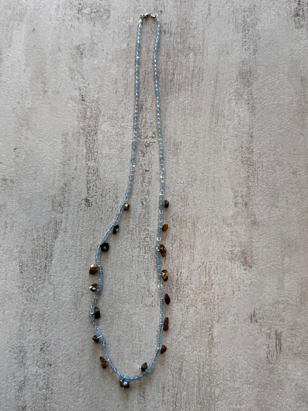 The full length of the necklace laid flat with the sterling silver lobster clasp at the top