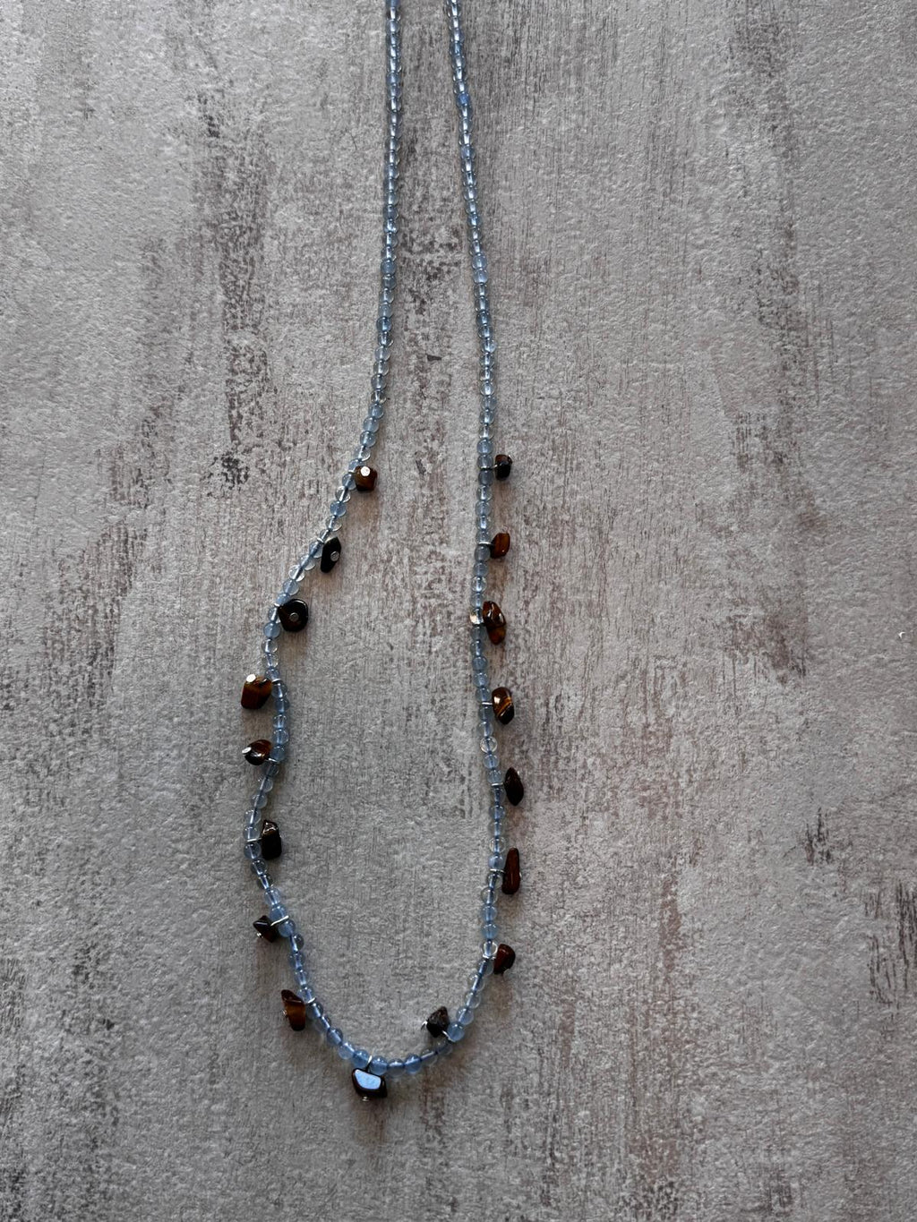 Close view of the translucent aquamarine beads and the irregular tiger's eye nuggets hung between them