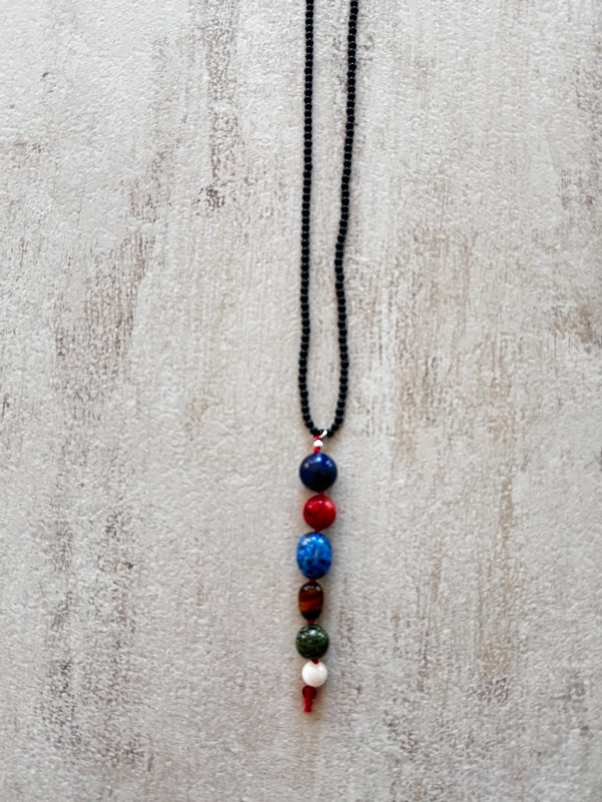 Close view of the drop: lapis lazuli, coral, kyanite, tiger's eye, green jasper and mother of pearl stacked in a column, knotted with red