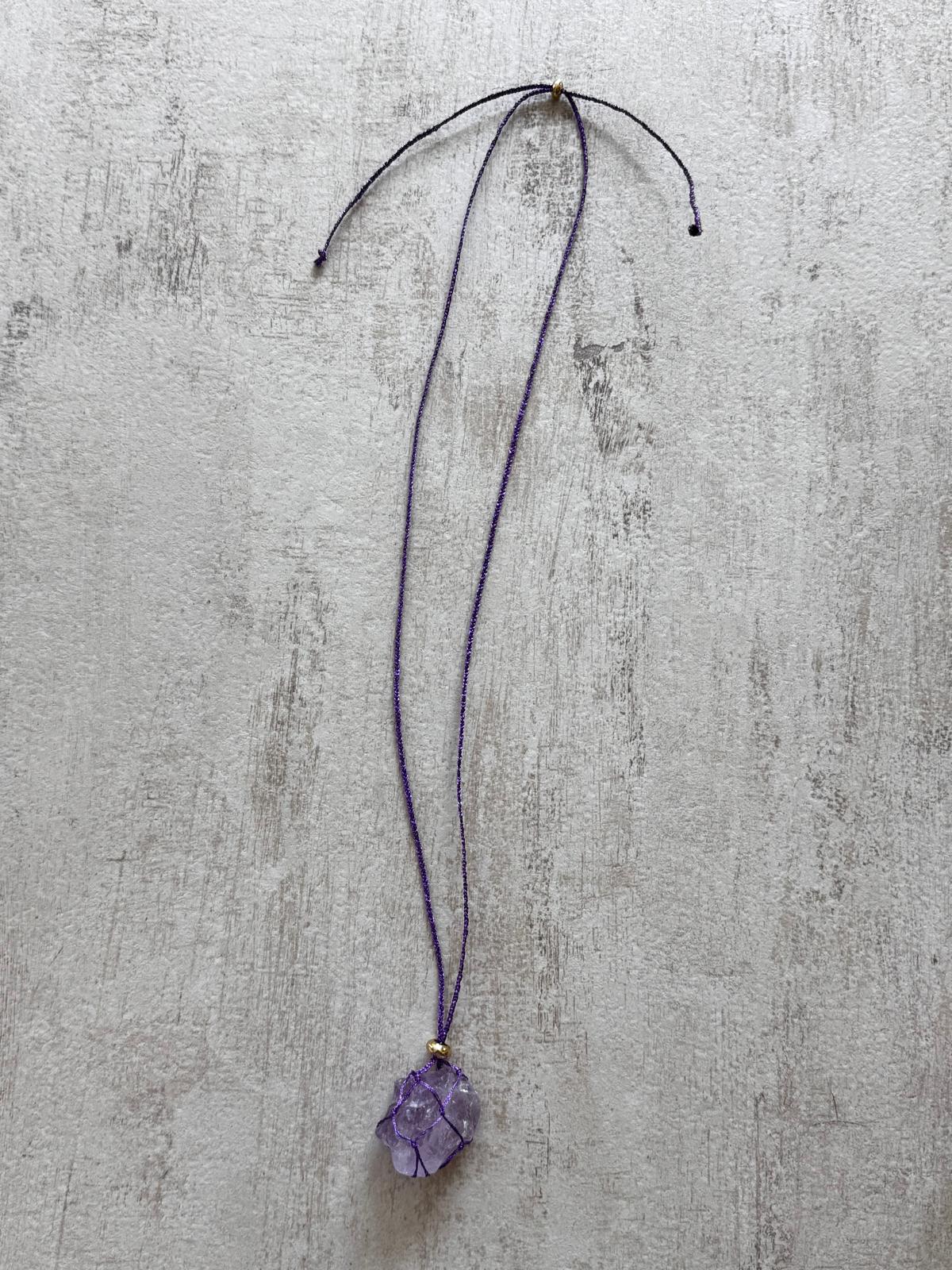 Full view of the raw amethyst pendant necklace on its purple cord with sliding adjuster